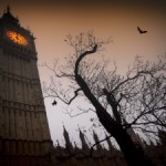 The spooky clock tower of Westminster with a bare tree and flying bats