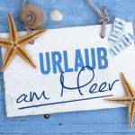 Urlaub an der Ostsee, Nordsee, Meer mit maritimer Dekoration auf blauen Holzhintergrund